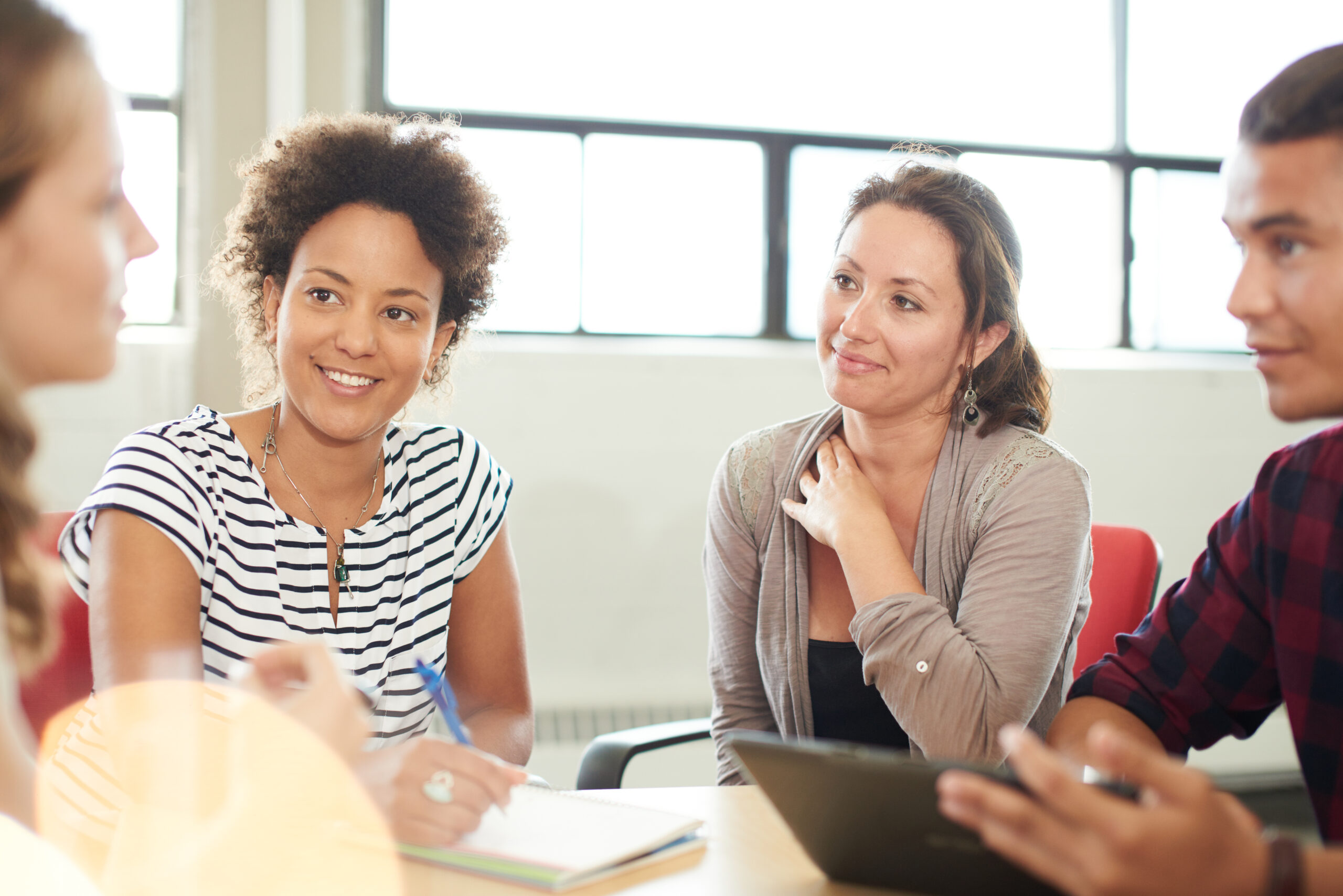 Candid picture of a startup business team collaborating on their next design project and using technology. Filtered serie with light flares, bokeh and warm sunny tones.